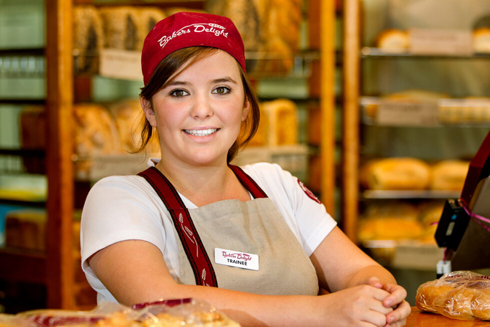 Professional commercial portrait of a bakery employee in a retail bakery, photographed to showcase customer service, workplace culture and brand personality.
