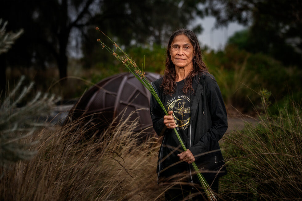 Environmental portrait of a woman holding native reeds in bushland during a community cultural project in South Australia.