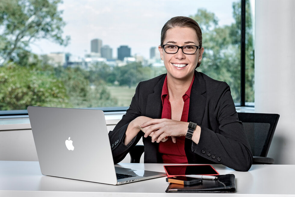 Professional portrait of a business executive photographed in a contemporary office overlooking the Adelaide skyline.