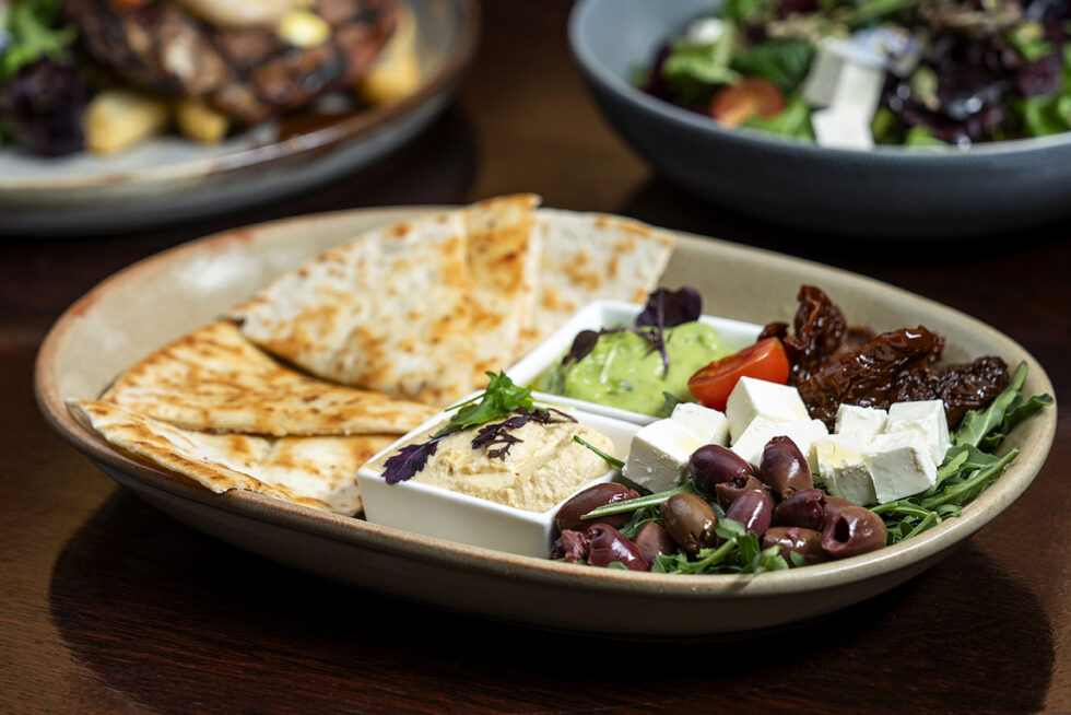 Mediterranean grazing platter professionally photographed for restaurant marketing, featuring hummus, feta, olives, flatbread and fresh seasonal ingredients.