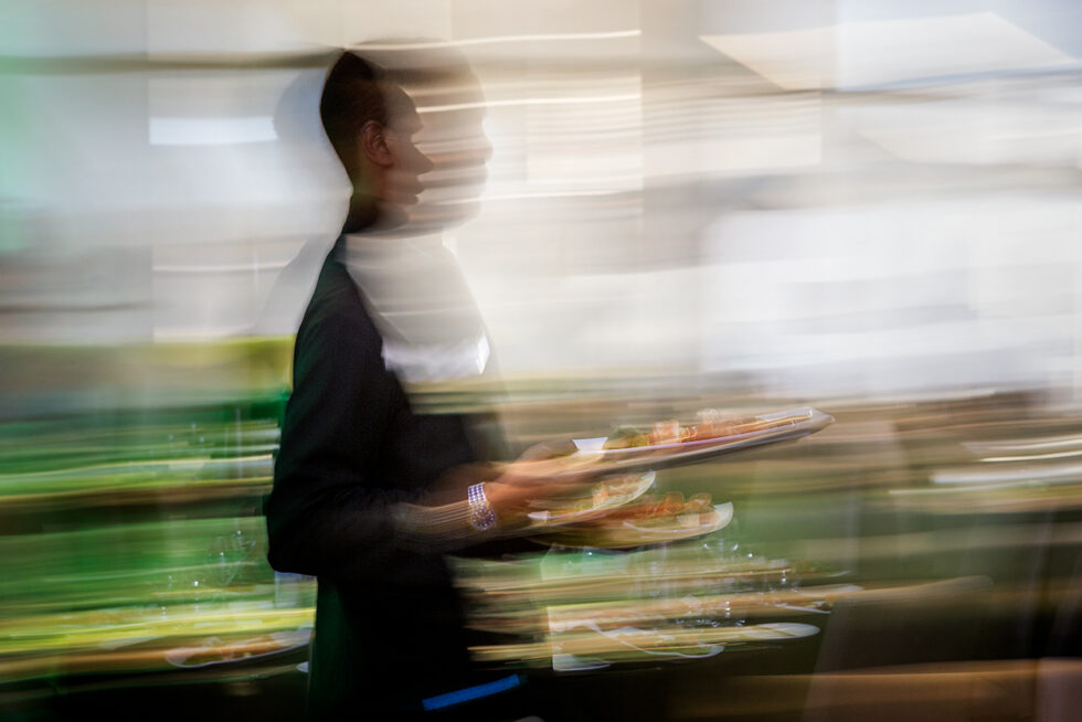 Creative long exposure photograph of a restaurant waiter serving food, illustrating the fast-paced atmosphere of a busy hospitality venue in Adelaide.