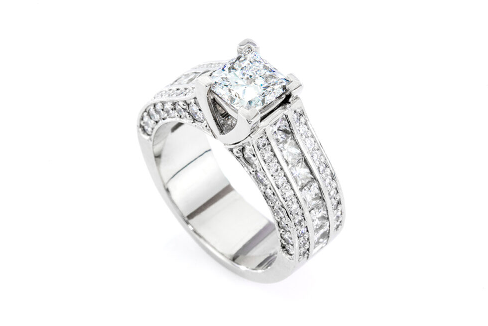 Studio product photograph of a diamond engagement ring with a princess-cut centre stone on a white background.