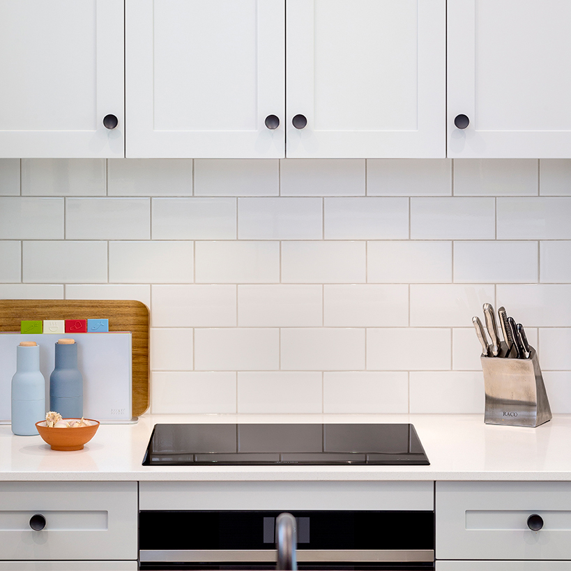 Modern white kitchen with subway tile splashback, stone benchtops and contemporary cabinetry photographed by Australian interior photographer John Nieddu.